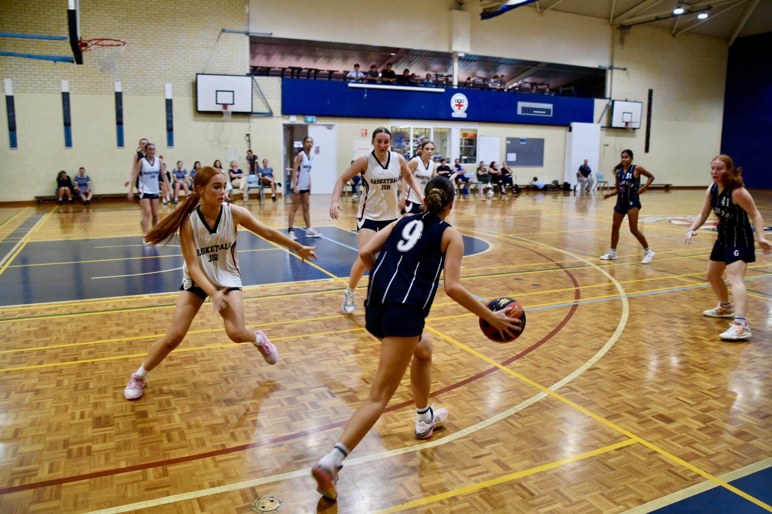 GGS students competing in a Basketball match inside the school gymnasium, summer season