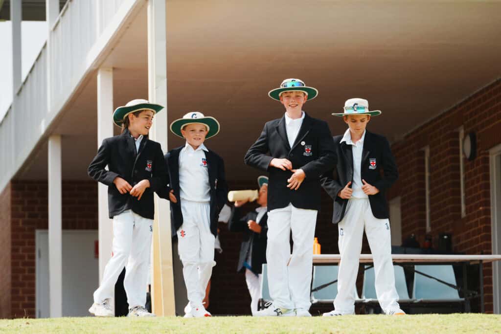 Group of students in blazers and hats engaging in a sports activity.