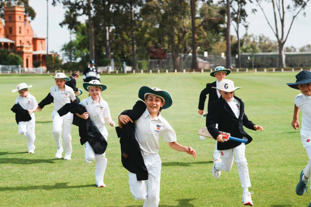 Guildford Grammar School students in sports uniforms running on a field.